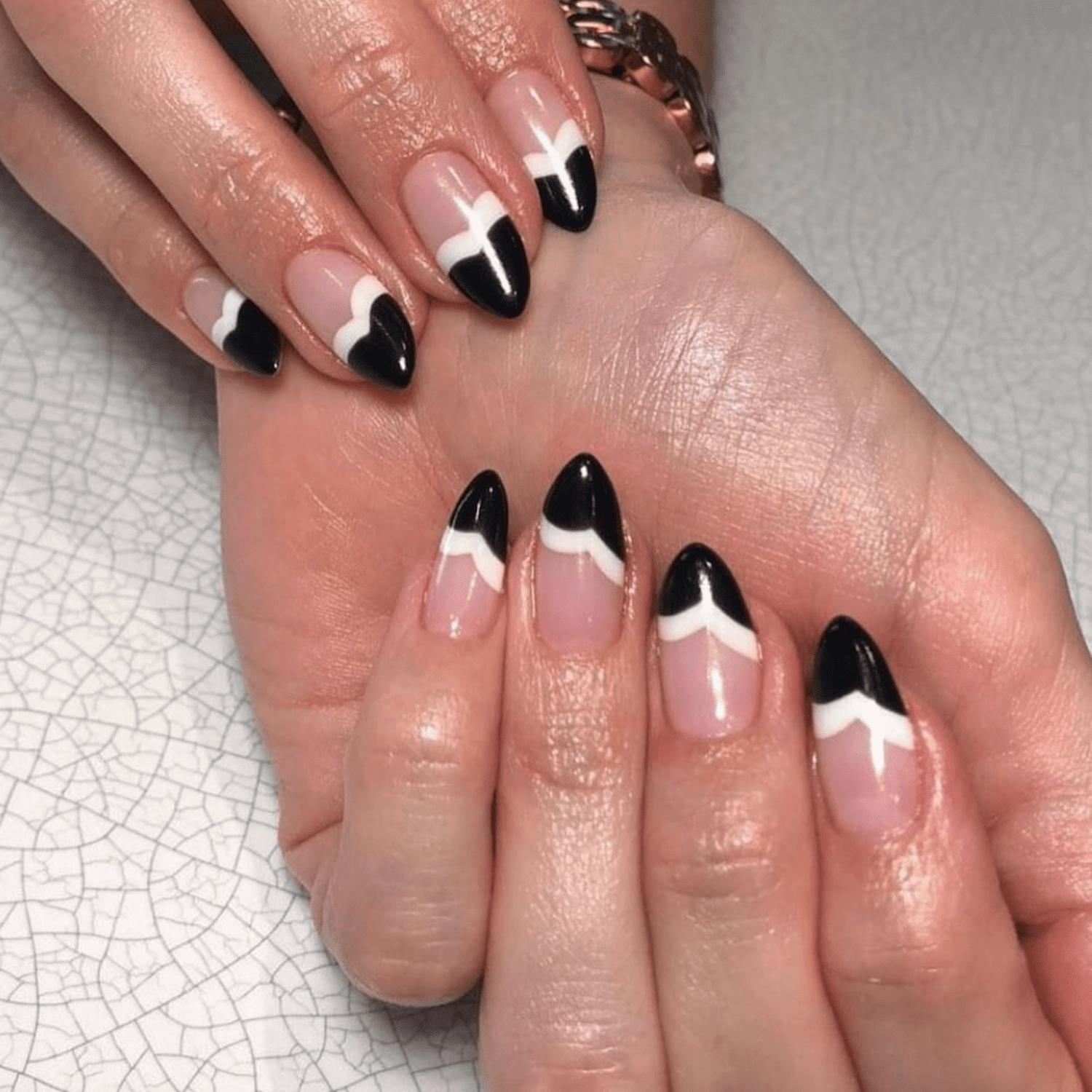 Manicure com pontas francesas brancas e pretas com uma forma de engrenagem