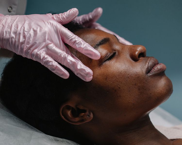 Uma mulher recebe sua massagem no rosto de um profissional.
